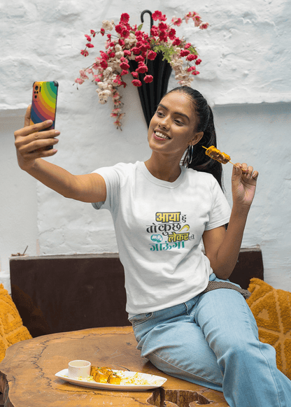 Woman taking a selfie while wearing unisex AYA HU KUCH TOH LEKE JAUNGA T-shirt and eating dessert