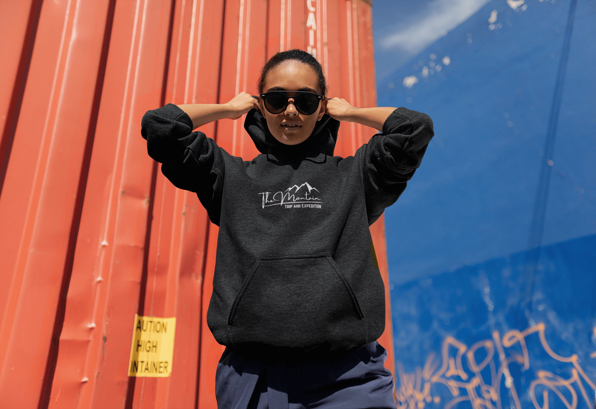 Model wearing a black hooded sweatshirt against a colorful urban backdrop, showcasing style and comfort.
